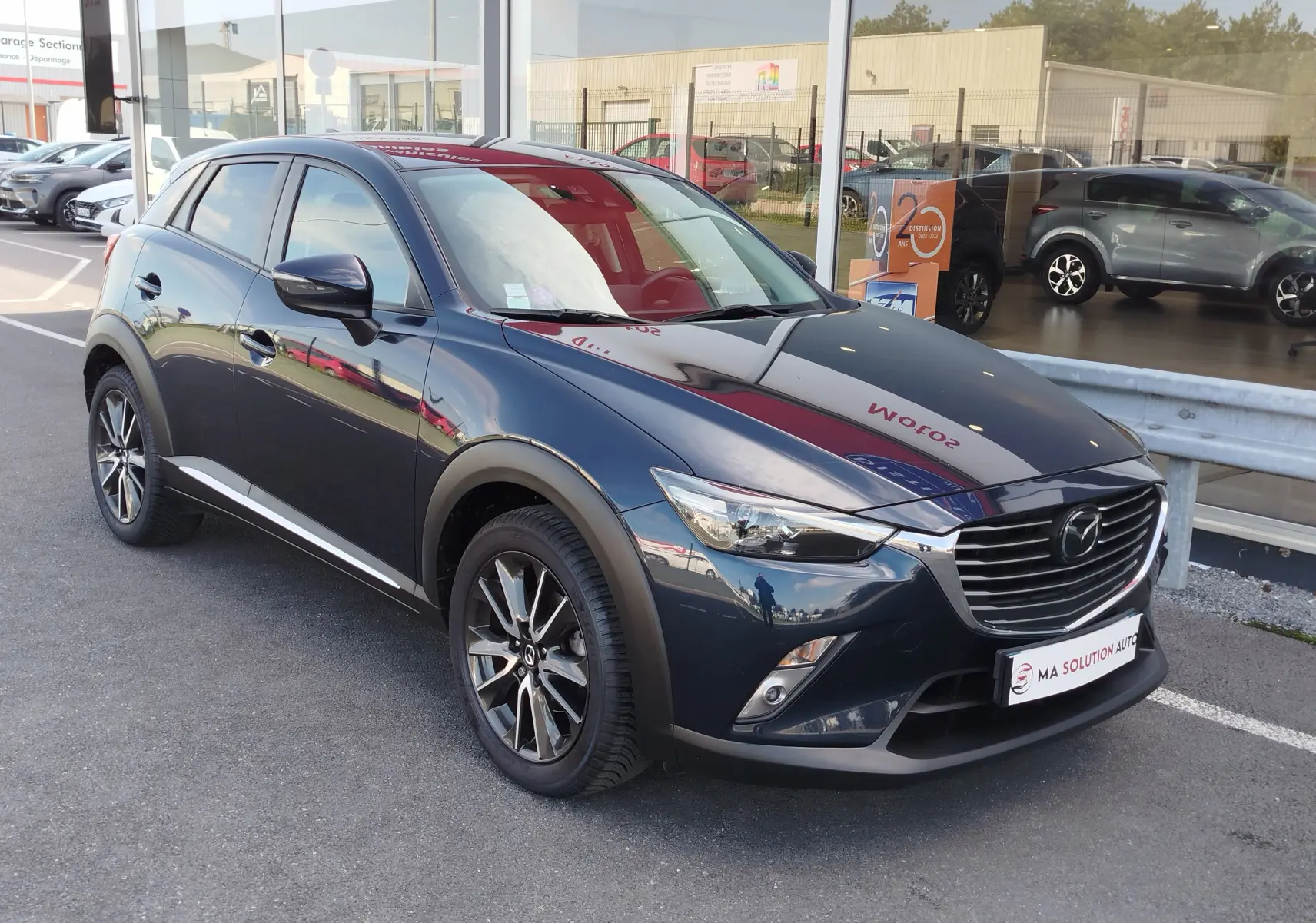 Mazda CX-3 2016 bleu Dynamic Blue Mica en 3/4 avant droit, avec jantes alliage et calandre chromée.