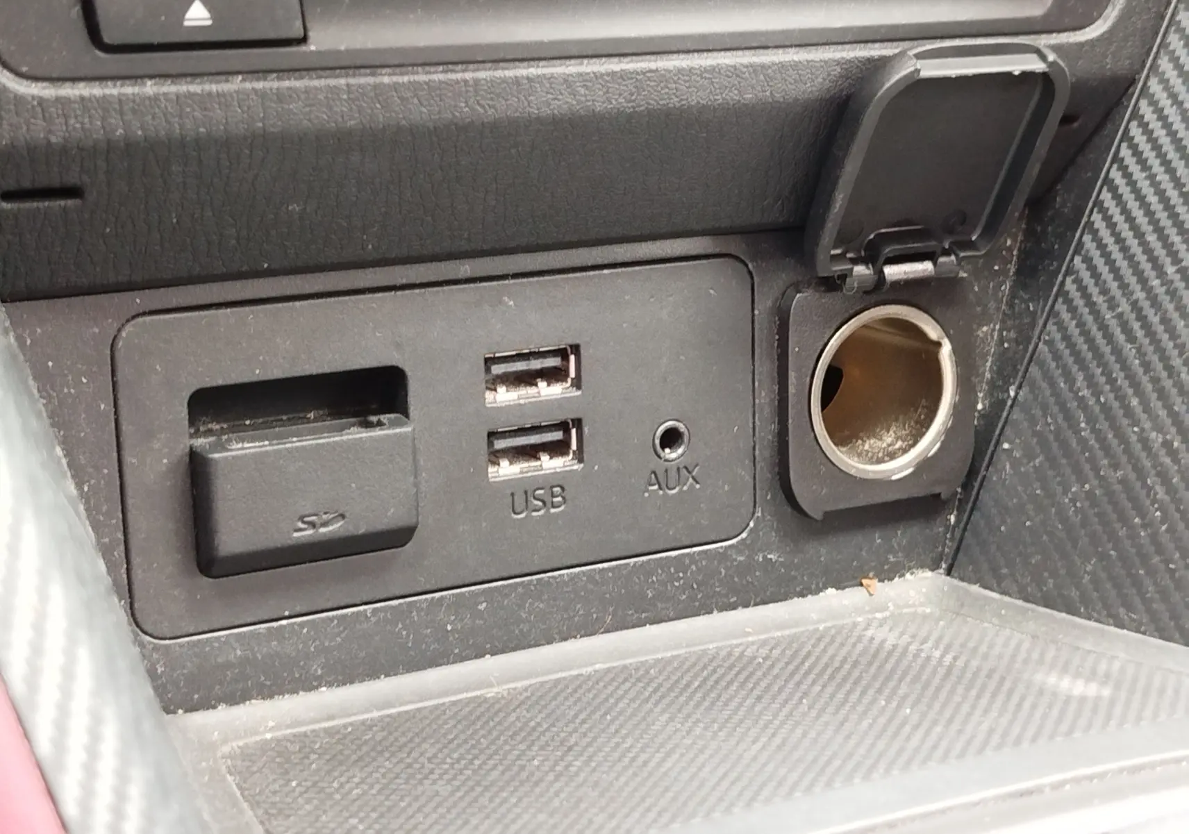 Gros plan sur la console centrale du Mazda CX-3 2016 montrant les ports USB, SD et prise 12V avec couvercle ouvert.