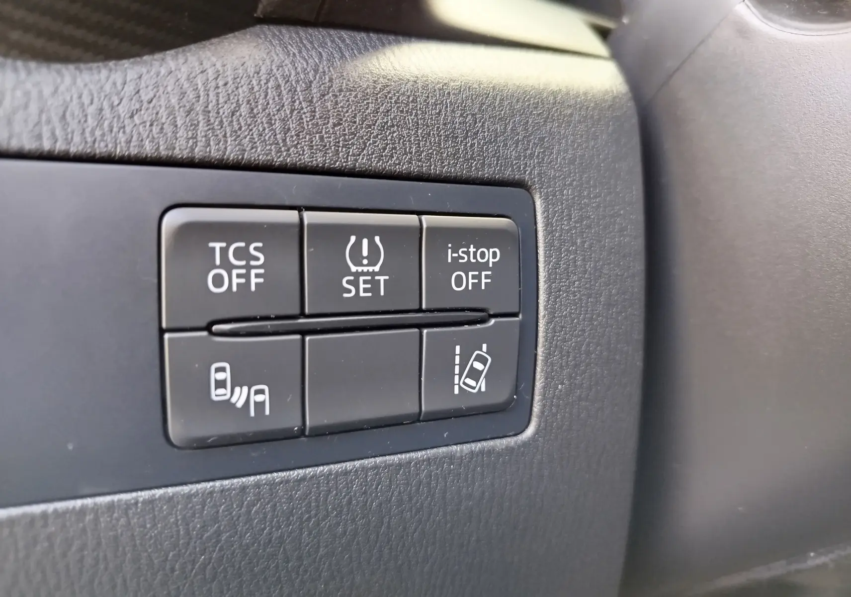 Gros plan sur les boutons de contrôle d'assistance à la conduite dans le tableau de bord noir du Mazda CX-3 2016.