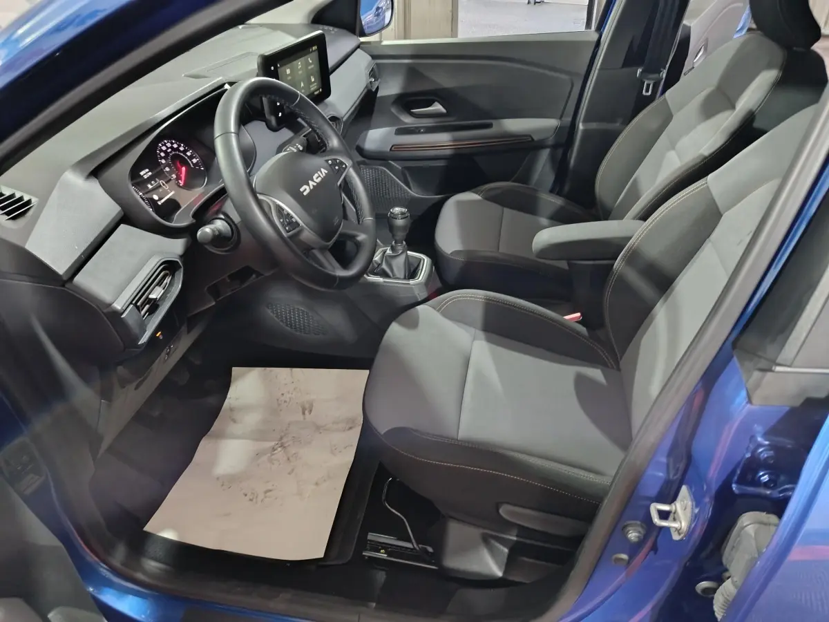 Vue intérieure côté conducteur de la Dacia Sandero Extreme+ 2024 bleu, volant cuir multifonctions et tableau de bord tactile.