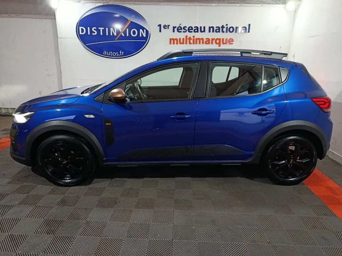 Profil droit d'une Dacia Sandero Extreme+ TCe 110 bleu avec jantes noires et rétroviseurs couleur bronze.