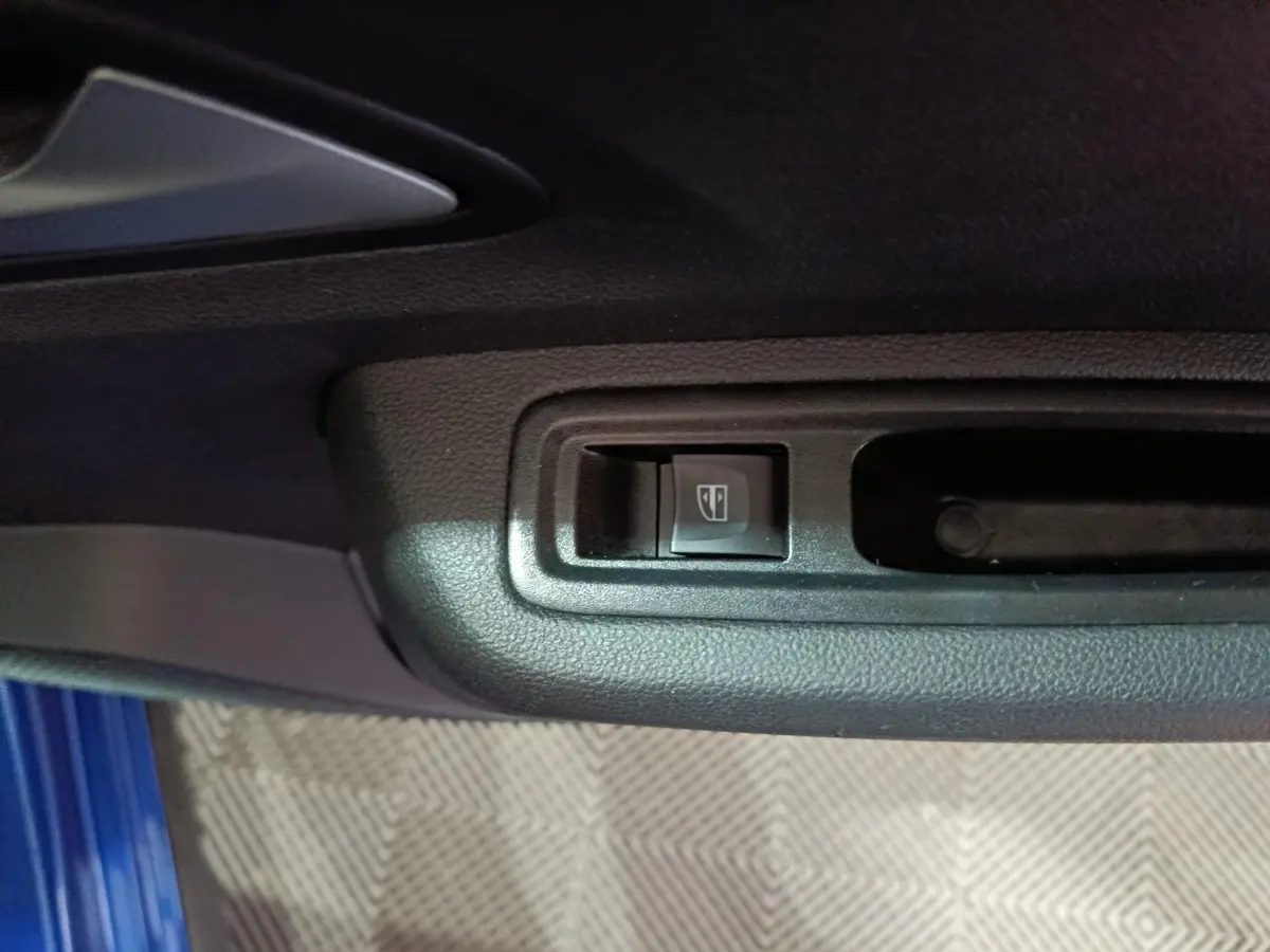 Gros plan sur le bouton de commande de la vitre électrique côté conducteur d'une Dacia Sandero Extreme+ bleu 2024.