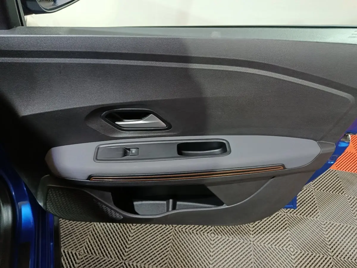 Vue rapprochée de la porte avant gauche bleu de la Dacia Sandero Extreme+ avec poignée intérieure et bouton de verrouillage.