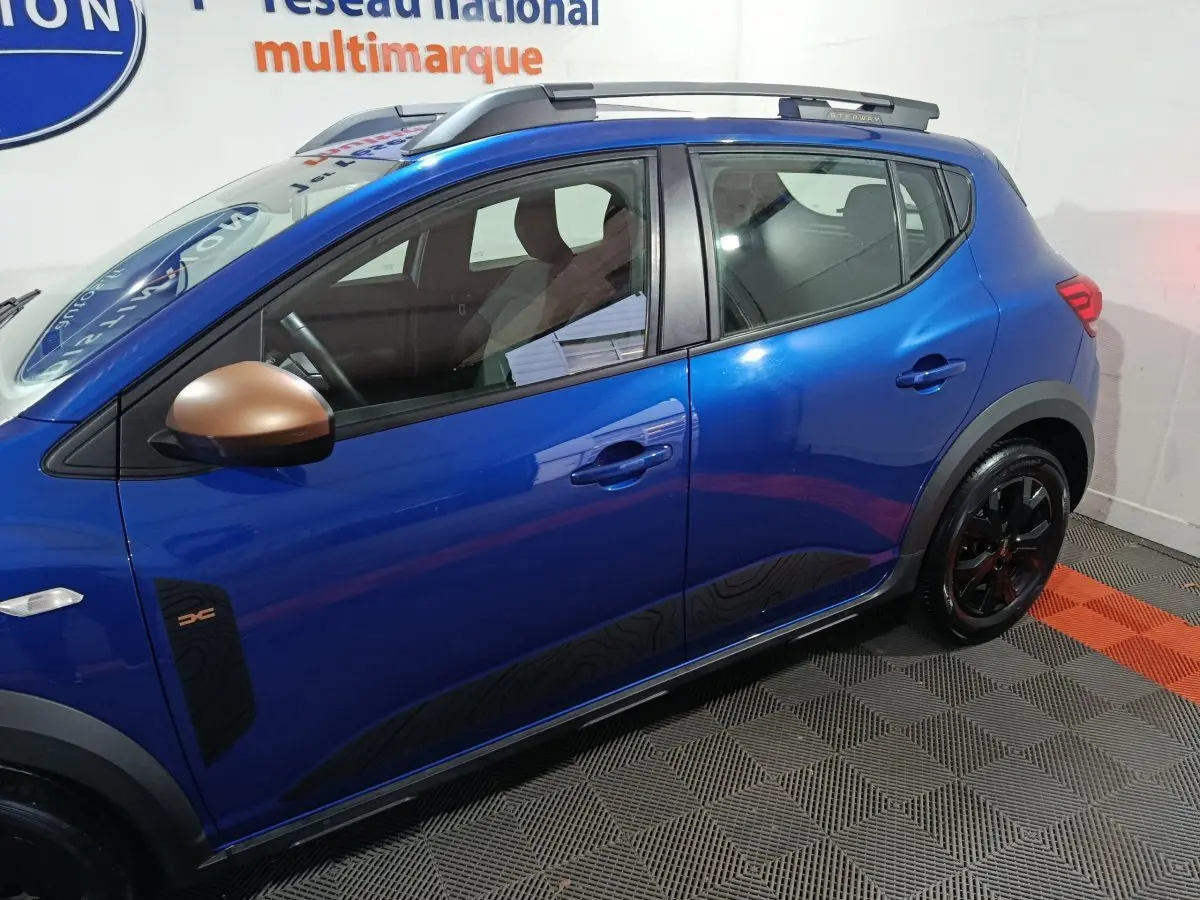 Vue latérale droite d'une Dacia Sandero Extreme+ bleu avec rétroviseurs bronze et jantes noires.