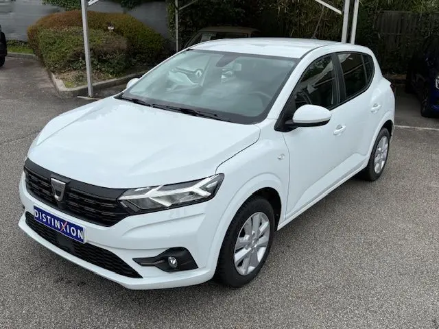Dacia Sandero 2023 blanc glacier vue 3/4 avant droit, avec calandre noire et phares LED distinctifs.