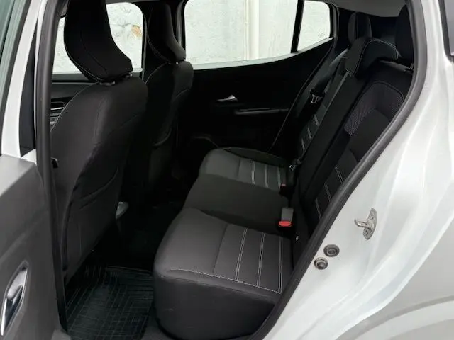 Vue intérieure arrière côté droit de la Dacia Sandero blanc glacier 2023, sièges tissu noir avec surpiqûres grises.