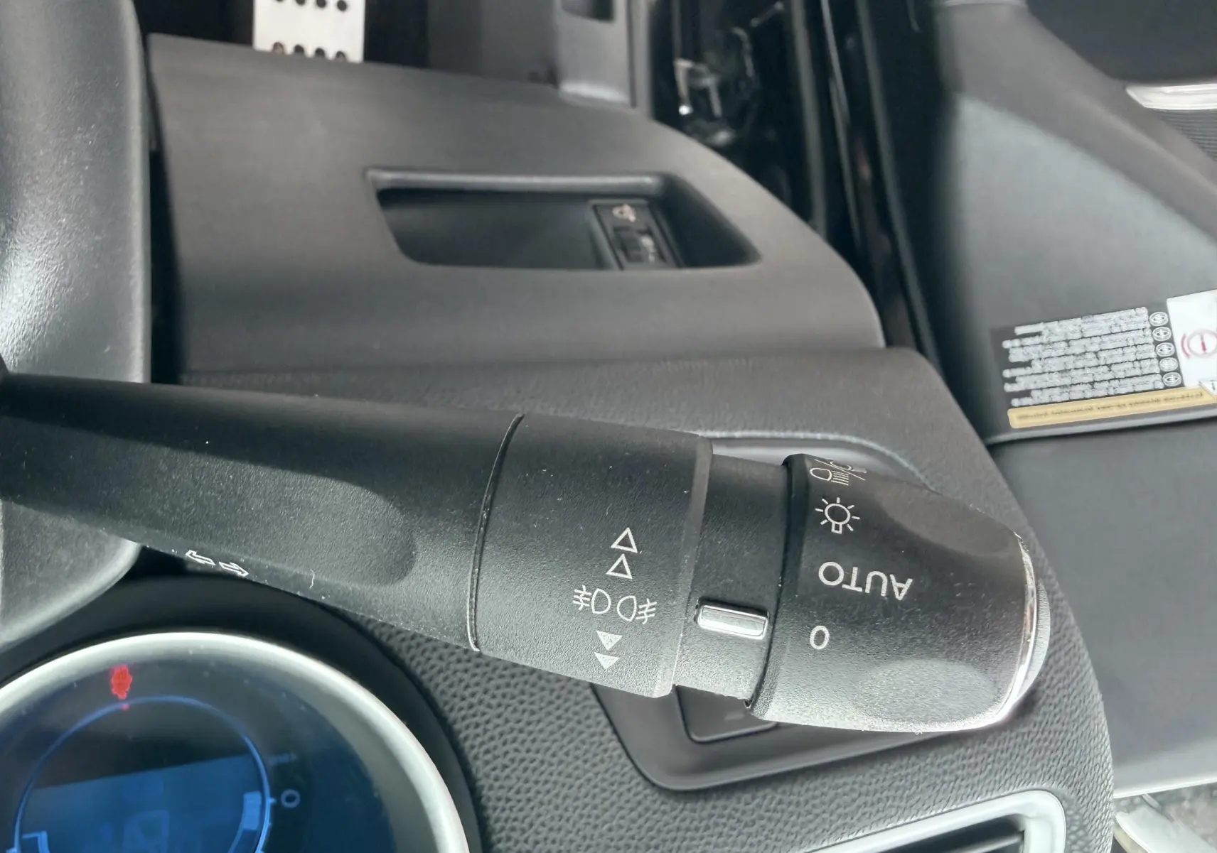 Gros plan sur la manette de commande d’éclairage noire dans l’habitacle d’une Citroën DS4 noire de 2012.