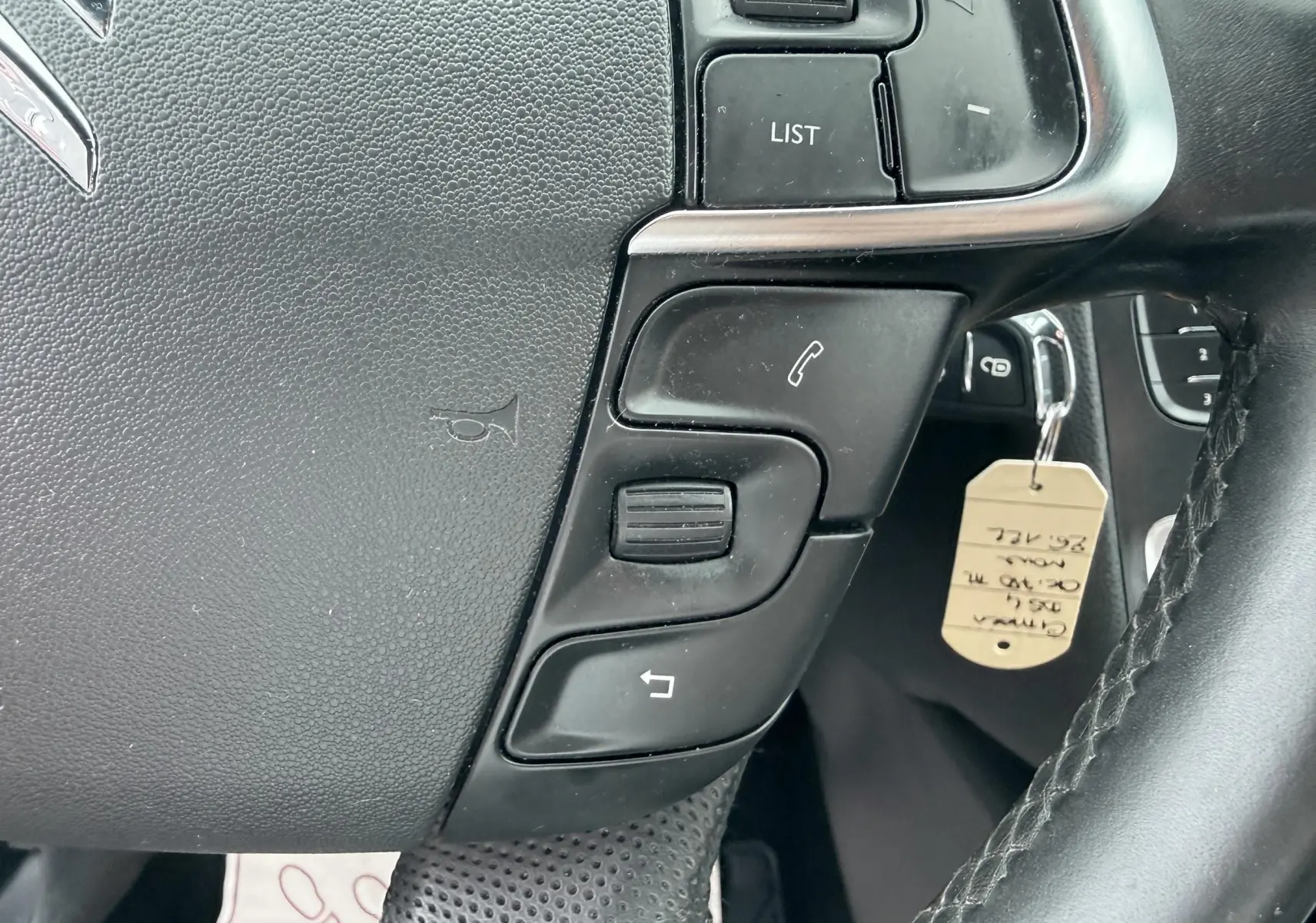 Gros plan sur les commandes du volant côté gauche d’une Citroën DS4 noire, avec touches de téléphonie et de menu.