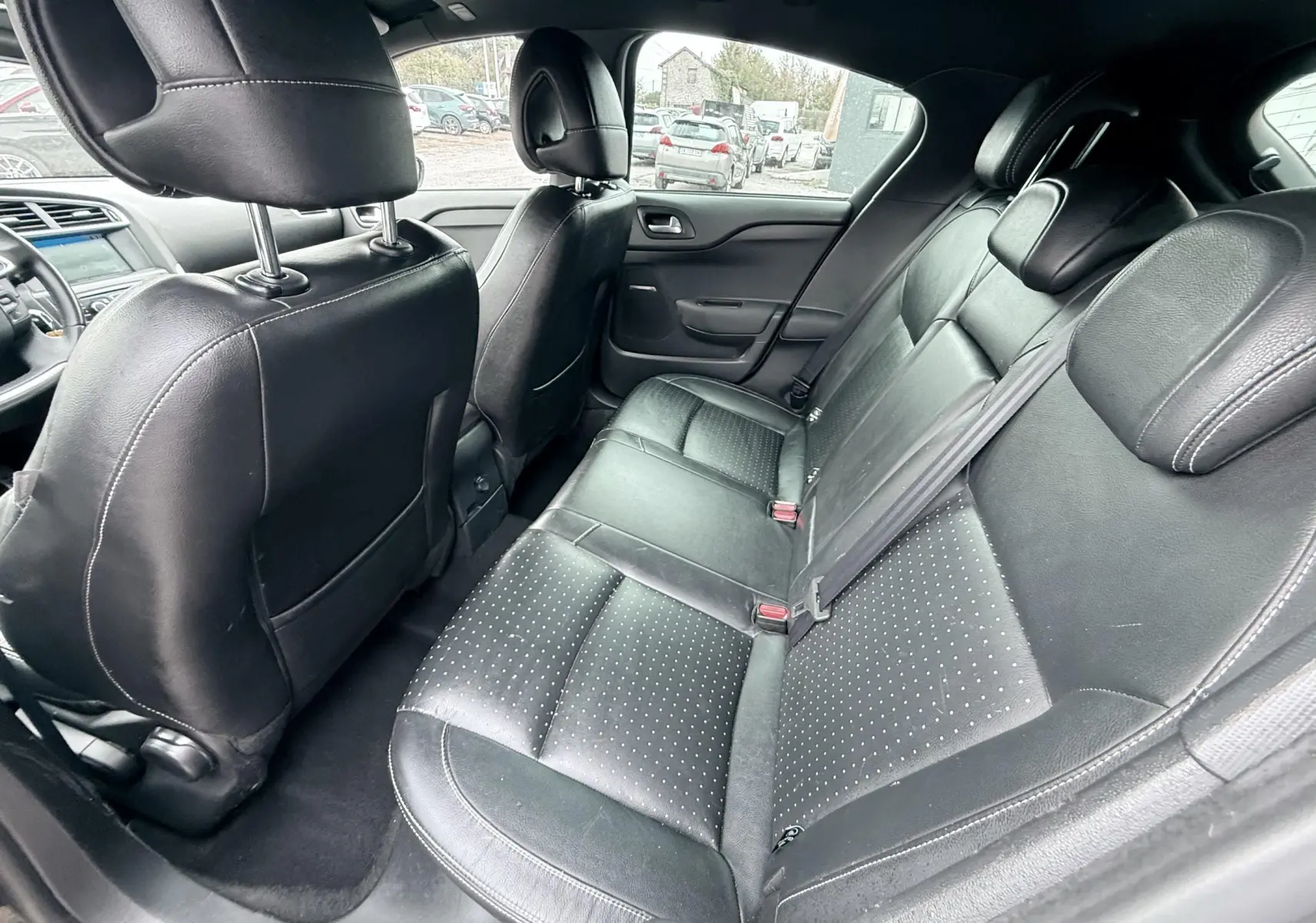 Vue intérieure arrière de la Citroën DS4 2012, sièges en cuir noir avec surpiqûres et ceintures visibles.