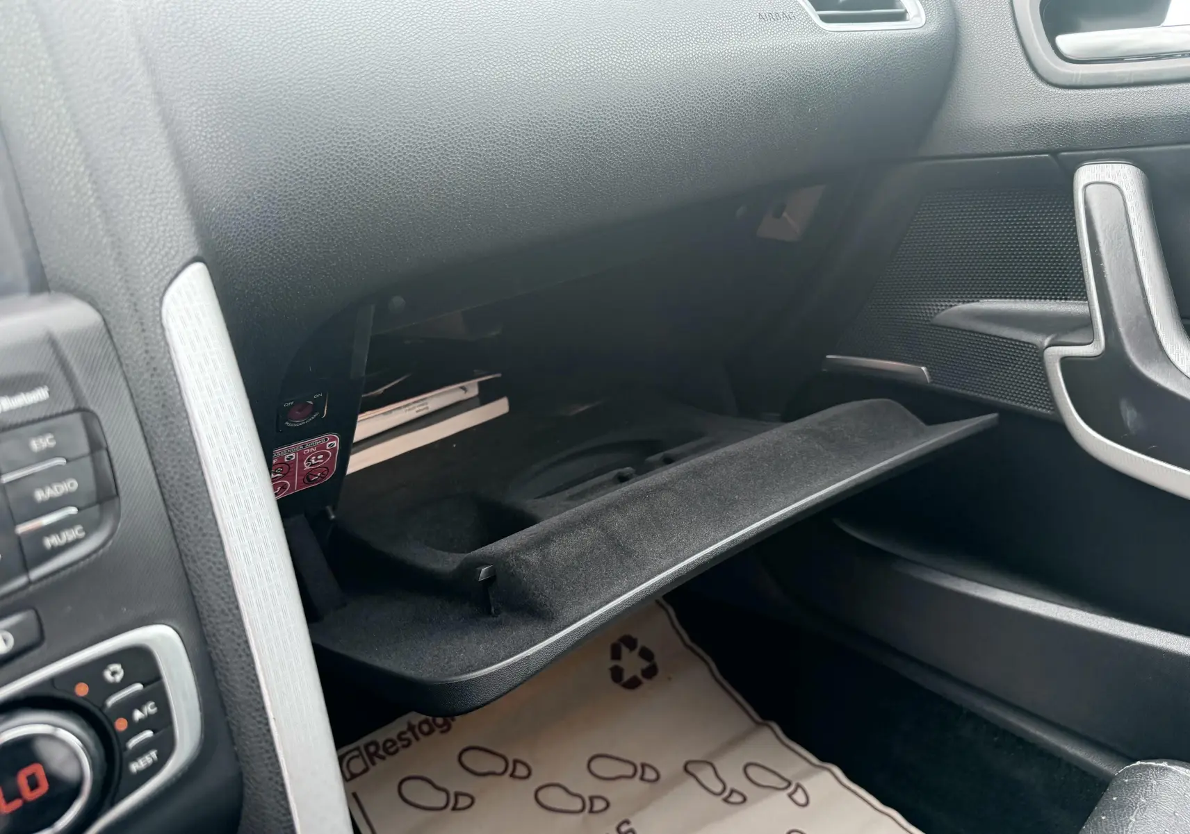 Vue intérieure côté passager du coffre à gants ouvert d'une Citroën DS4 noire de 2012, avec plancher protégé par tapis.