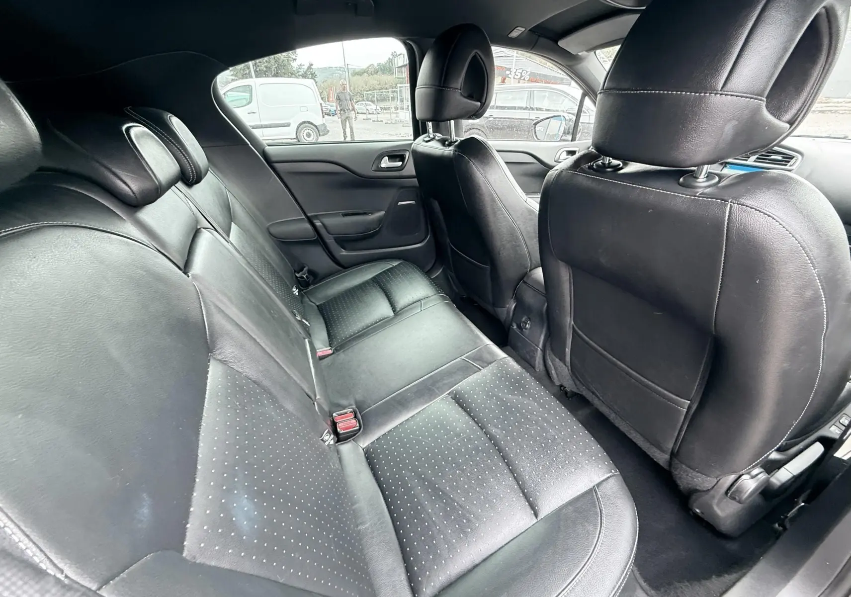 Vue intérieure arrière de la Citroën DS4 2012, sièges en cuir noir et finition perforée, ambiance sobre et élégante.