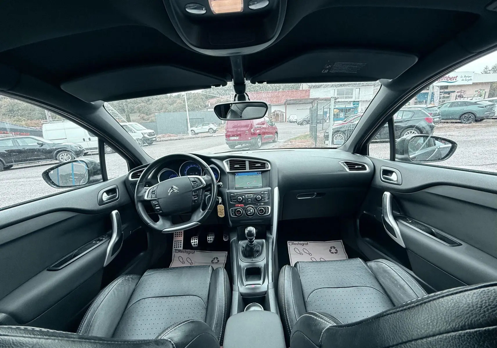Vue intérieure avant de la Citroën DS4 noire, montrant le tableau de bord, volant cuir et console centrale avec boîte manuelle.