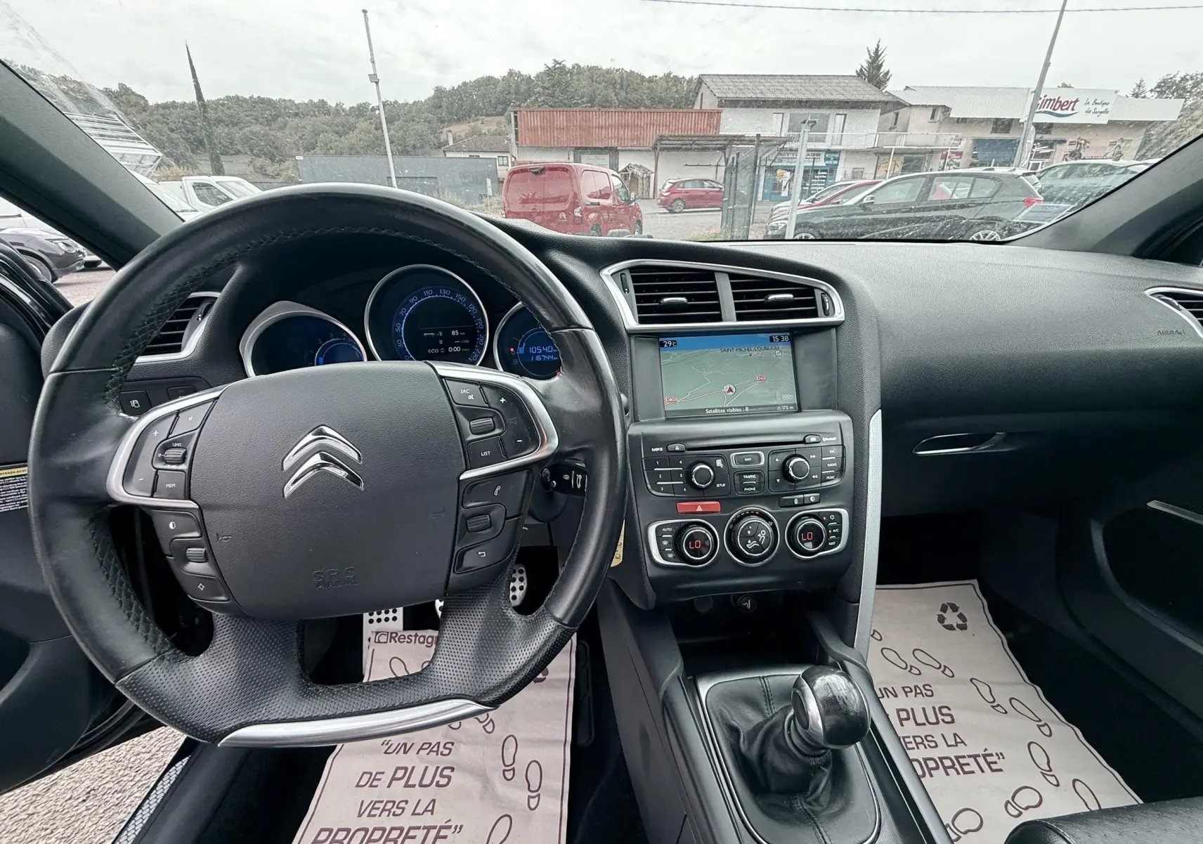 Vue intérieure avant de la Citroën DS4 noire de 2012, mettant en valeur le volant cuir et la console centrale avec écran GPS.