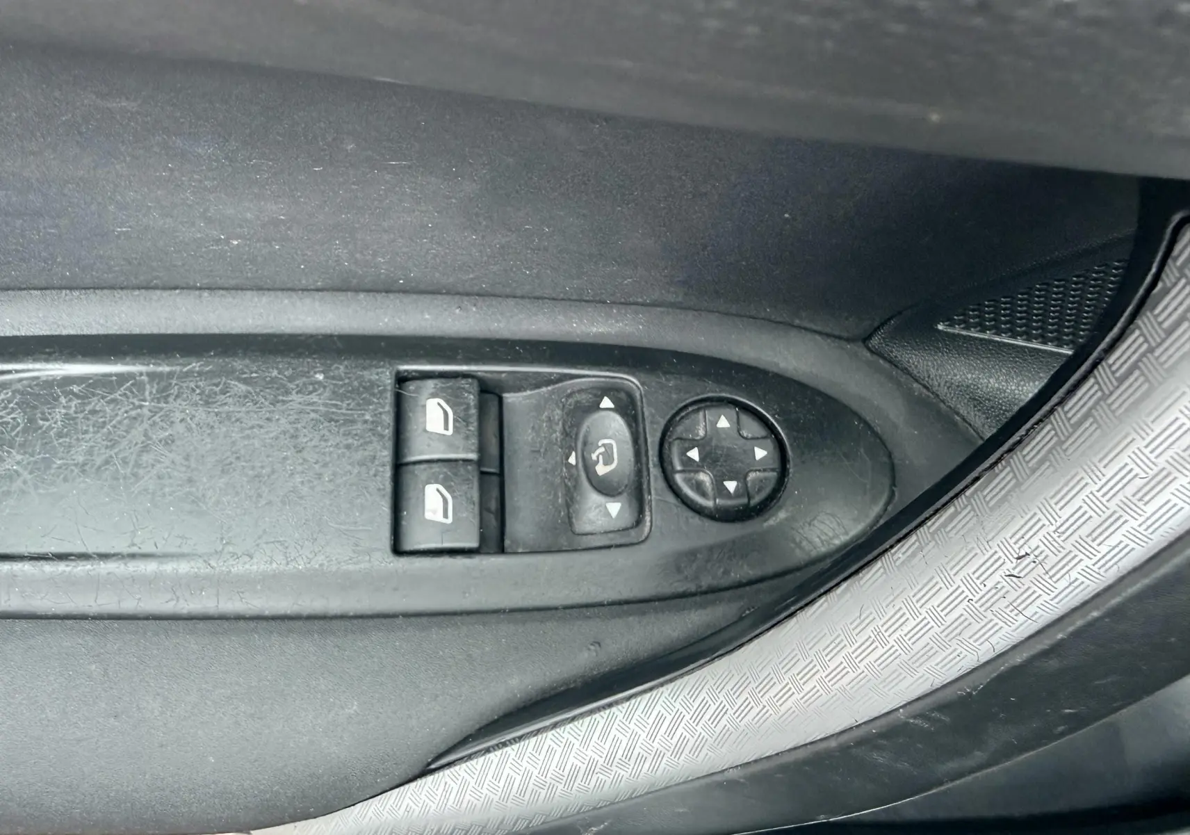 Gros plan sur les commandes de lève-vitres et réglage des rétroviseurs côté conducteur d'une Citroën DS4 noire.