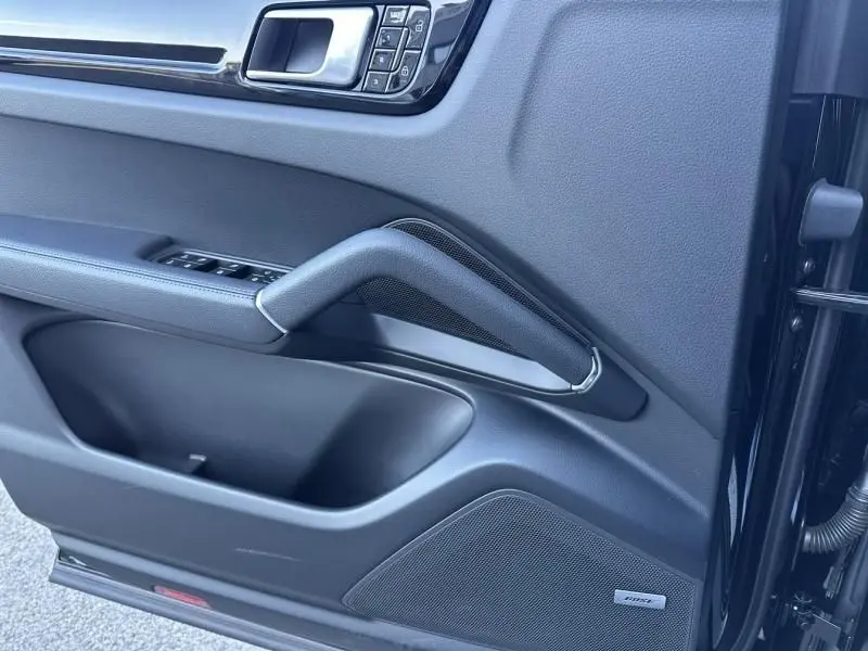 Détail de la porte côté gauche du Porsche Cayenne Coupé 2020 noir métal avec poignée et haut-parleur Bose intégrés.
