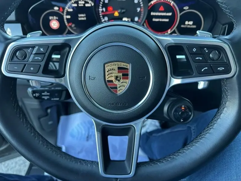 Vue rapprochée du volant cuir noir du Porsche Cayenne Coupe 3.0 V6 340CV 2020 avec commandes intégrées et tableau de bord numérique.