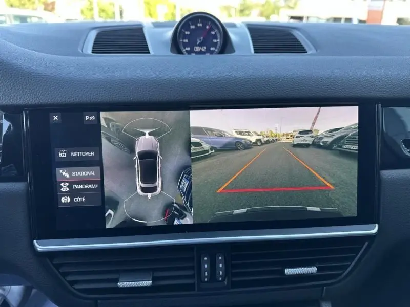 Vue intérieure du tableau de bord du Porsche Cayenne 2020 noir métal, écran affichant la caméra de recul et vue à 360° du véhicule.