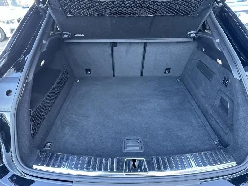 Coffre ouvert d'un Porsche Cayenne Coupe noir métal 2020, montrant un espace de chargement propre et doublé de moquette noire.
