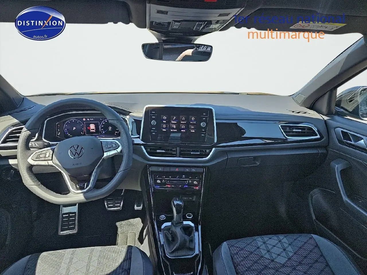 Vue avant de l'intérieur du Volkswagen T-Roc noir perle, avec volant cuir multifonction et écran tactile central.