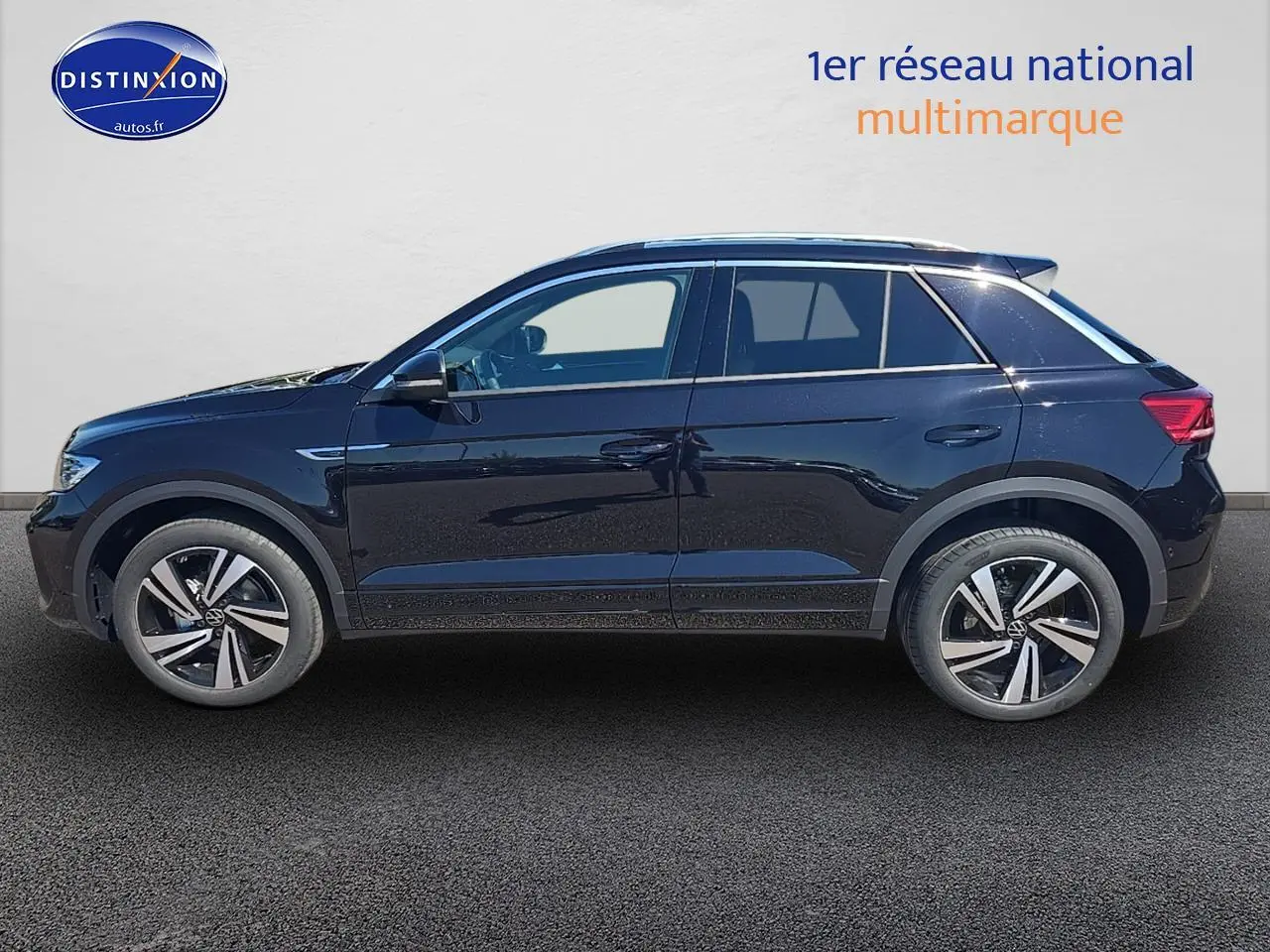 Profil latéral droit du Volkswagen T-Roc noir perle avec jantes alliage 18 pouces et barres de toit argentées.