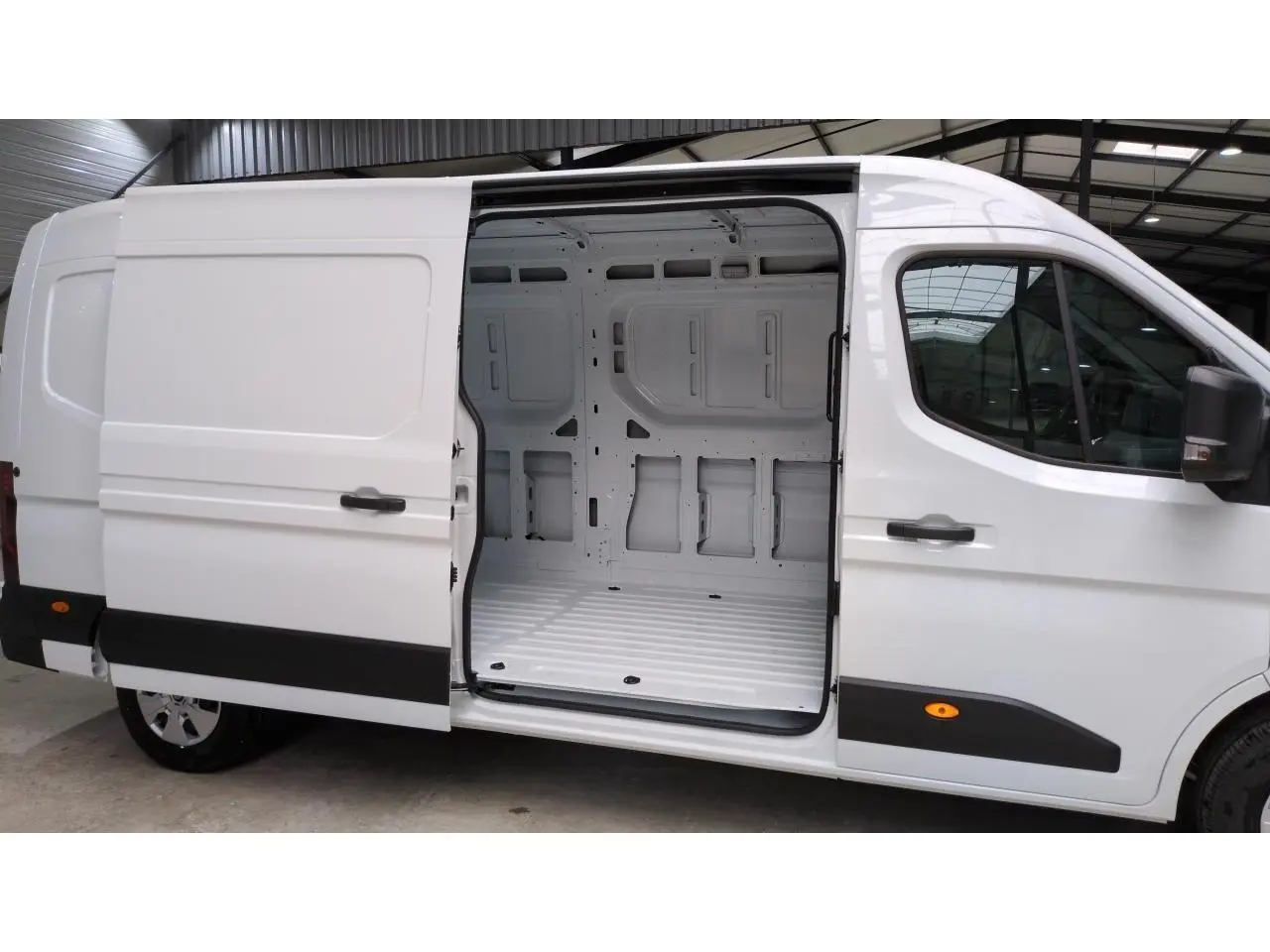Vue latérale droite d'un Renault Master blanc 2025 avec porte coulissante ouverte dévoilant l'espace de chargement vide.
