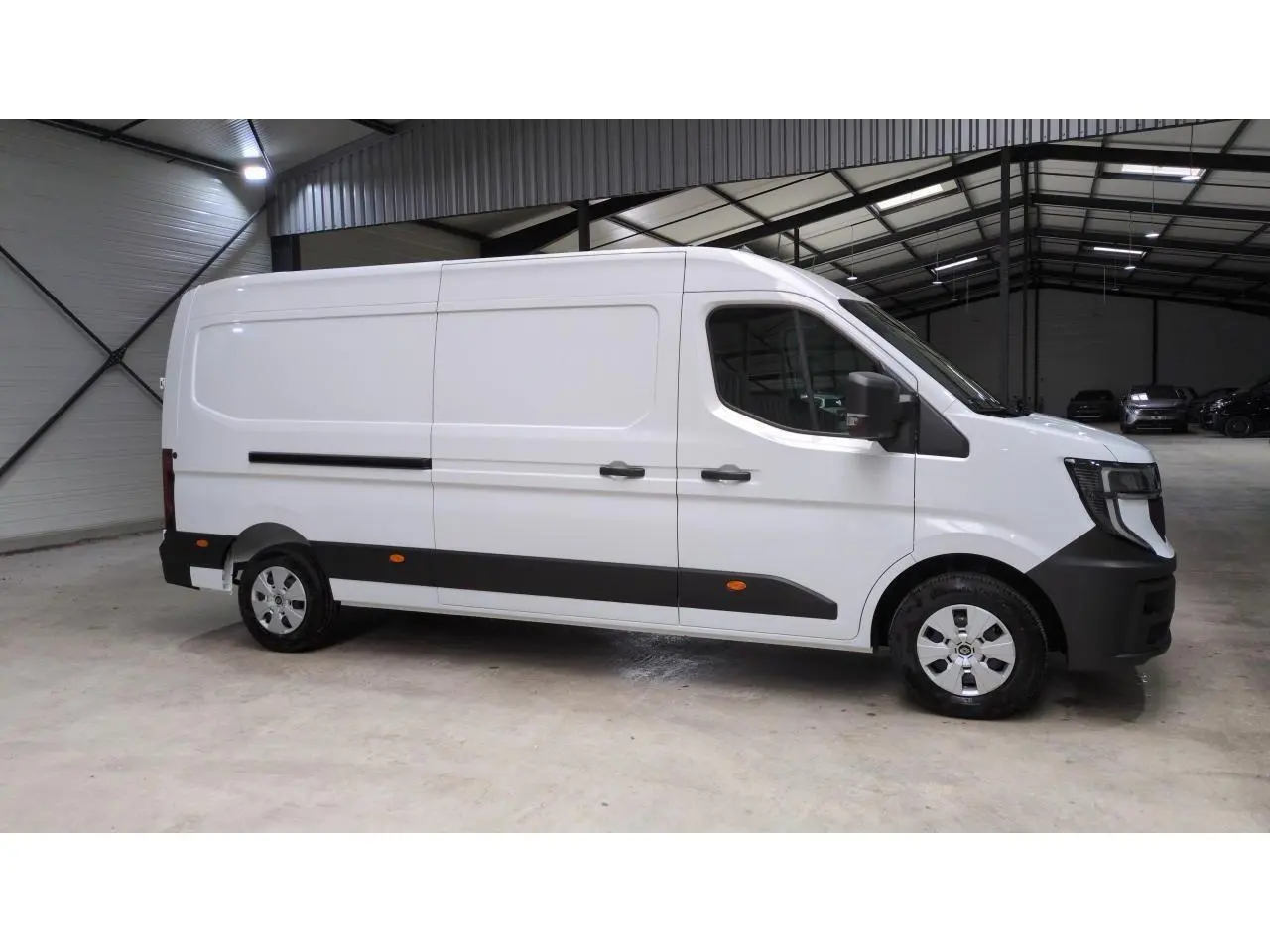 Vue latérale droite du Renault Master blanc 2025 avec bandes noires et jantes argentées dans un entrepôt.