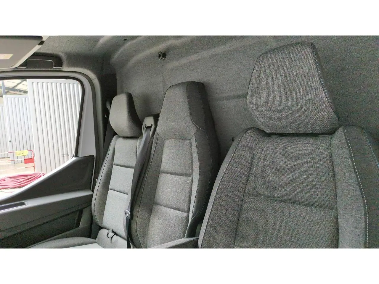 Intérieur du Renault Master 2025 vu de côté gauche, montrant les sièges gris en tissu et la porte conducteur ouverte.