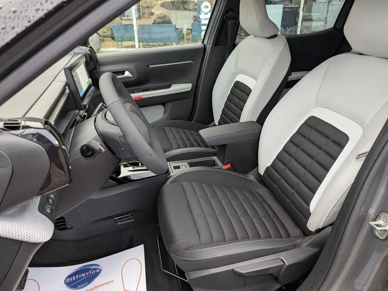 Intérieur avant droit du Citroën C3 Aircross 2025 avec sièges bicolores gris clair et noir, volant multifonctions et écran tactile.