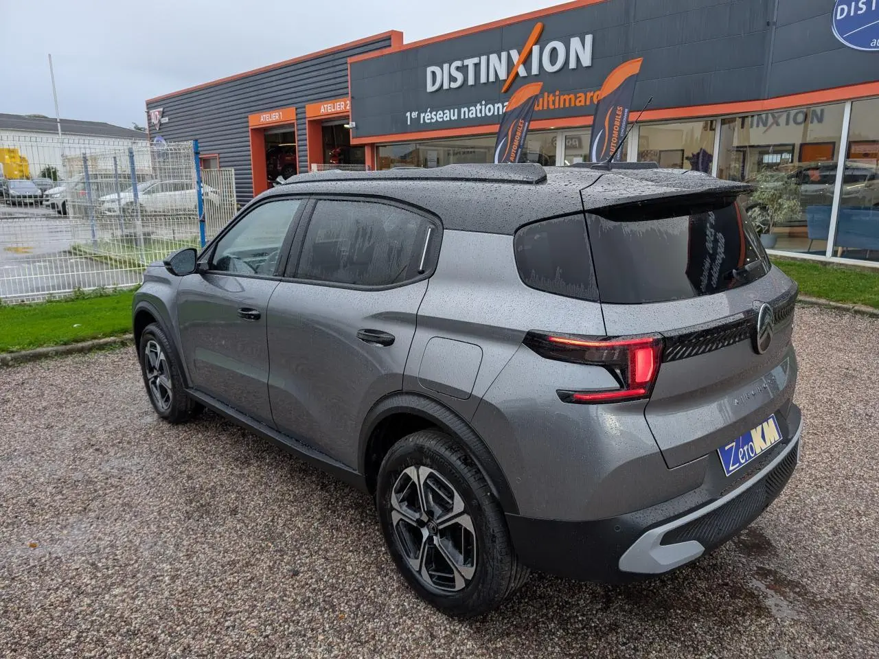 Vue 3/4 arrière droite d'un Citroën C3 Aircross 2025 gris métallisé avec toit noir et jantes diamantées.