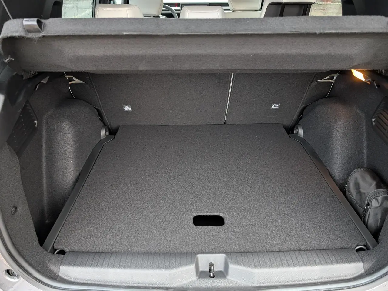 Coffre ouvert vu de l'arrière du Citroën C3 Aircross gris métallisé avec plancher de coffre plat et rangement noir.