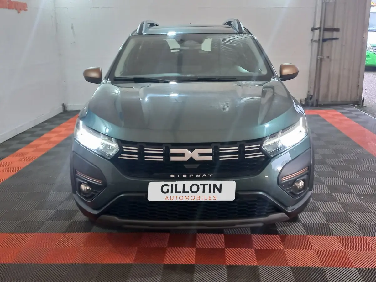 Vue avant d'une Dacia Sandero Extreme+ TCe 110 2024 vert, avec phares LED allumés et calandre noire distinctive.