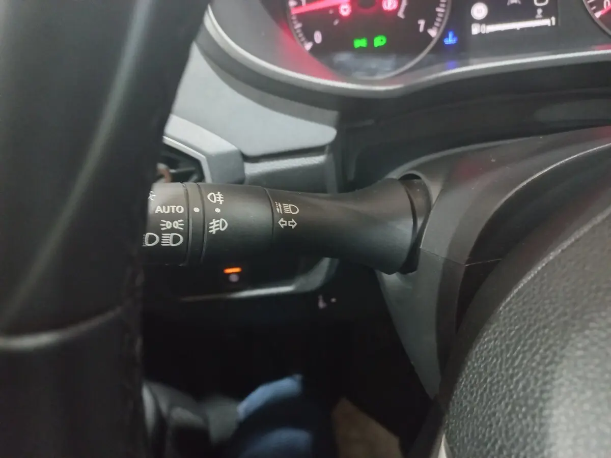 Gros plan sur la manette de commande des phares et clignotants du tableau de bord d'une Dacia Sandero 2024, intérieur noir.