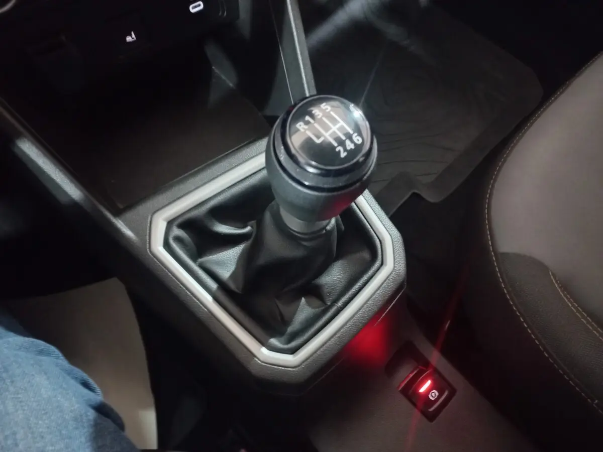 Gros plan sur le levier de vitesses manuel noir et la commande de frein à main électrique rouge dans l’habitacle d’une Dacia Sandero 2024.