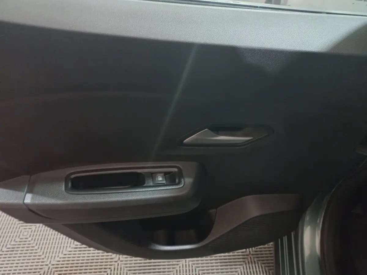 Vue intérieure du panneau de porte côté conducteur vert foncé de la Dacia Sandero Extreme+ TCe 110 2024 avec commande de lève-vitre électrique.