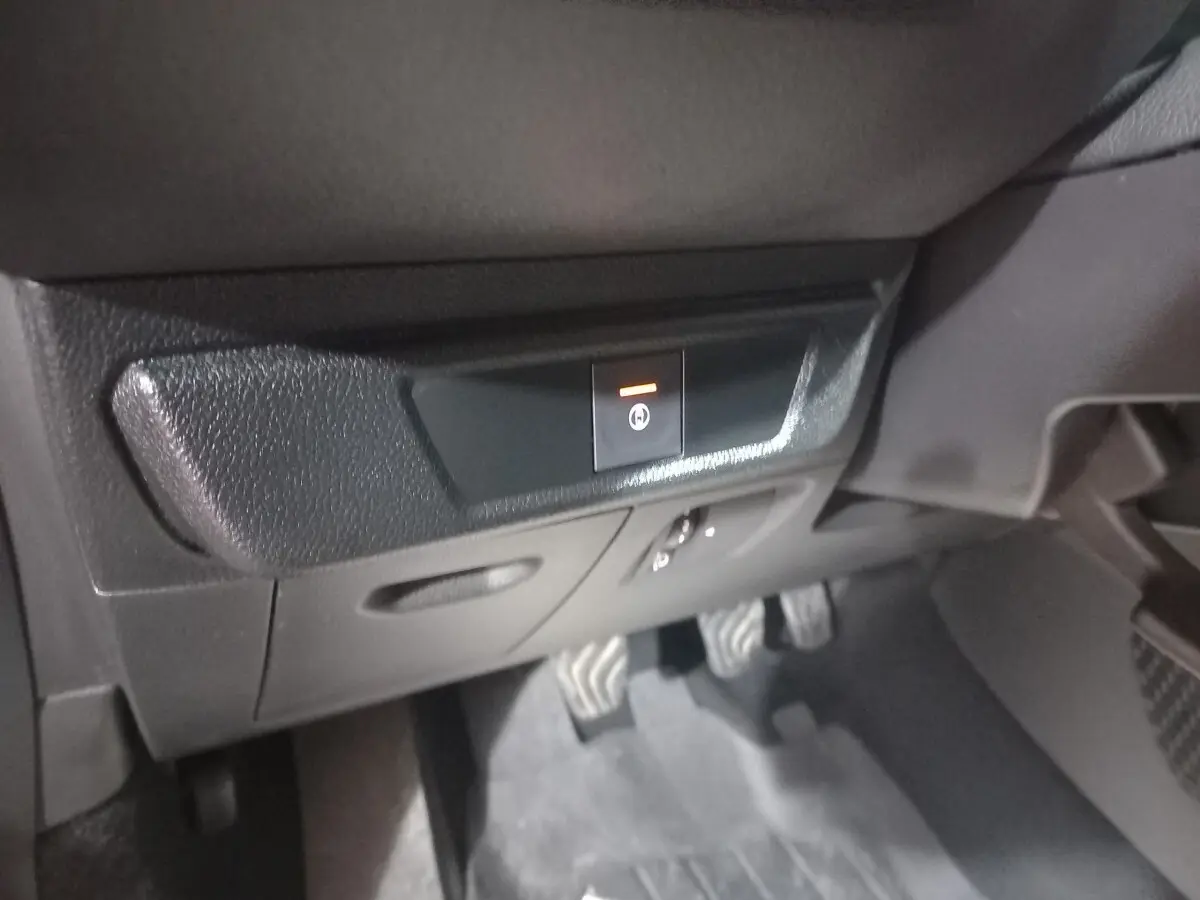 Gros plan sur le bouton de frein à main électrique dans l'habitacle noir d'une Dacia Sandero Extreme+ TCe 110 2024.