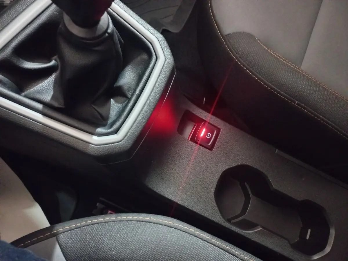 Gros plan sur la console centrale de la Dacia Sandero 2024, avec levier de vitesse manuel et frein à main électrique allumé.