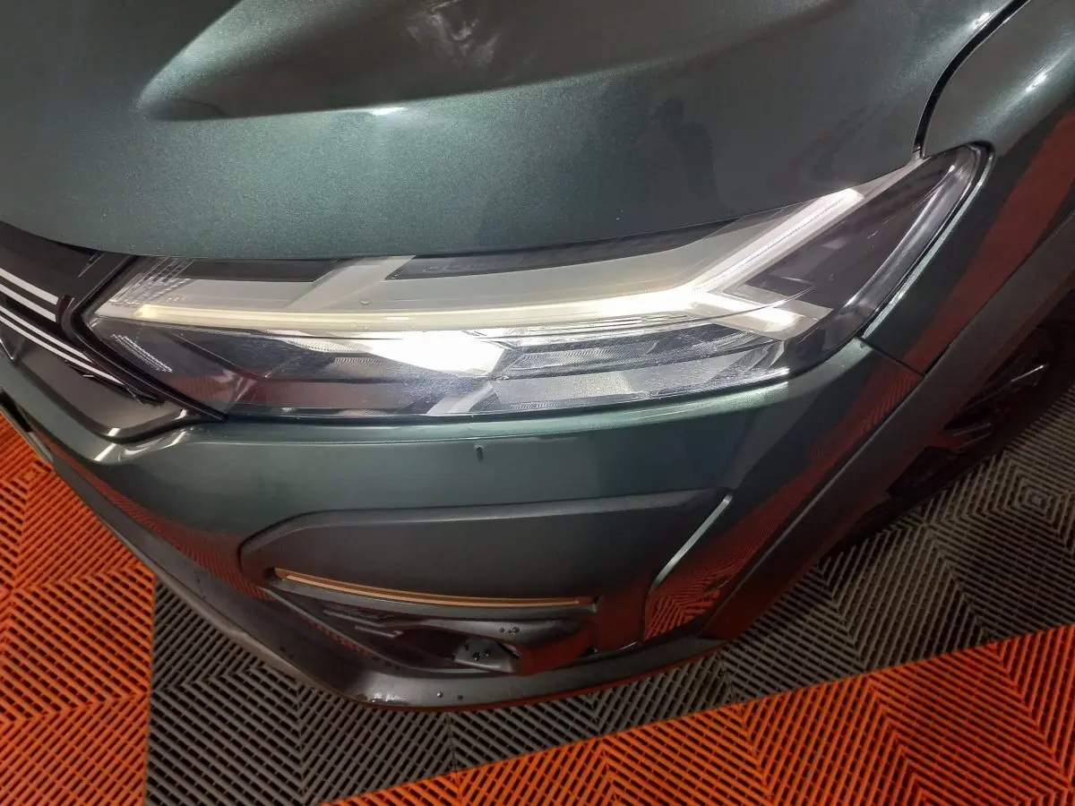 Gros plan sur le phare avant droit vert métallisé de la Dacia Sandero Extreme+ 2024 avec détails LED et pare-chocs noir.