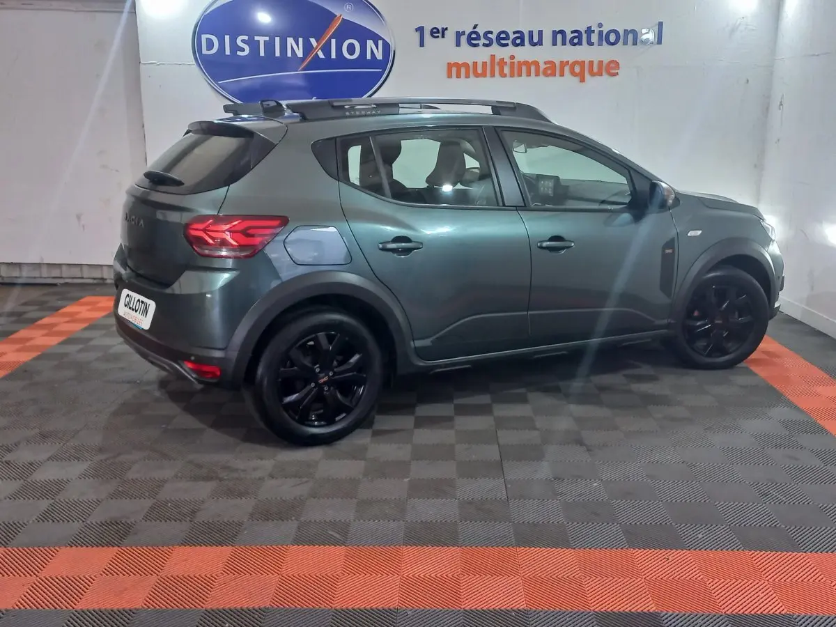 Vue de profil côté gauche d'une Dacia Sandero Extreme+ TCe 110 2024 vert métallisé avec jantes noires et barres de toit.