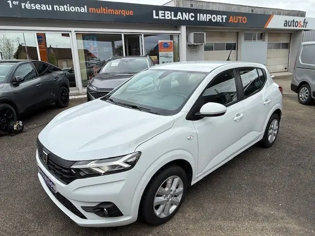 Vue 3/4 avant droite d'une Dacia Sandero 2023 blanc glacier, avec phares LED et jantes alliage visibles.