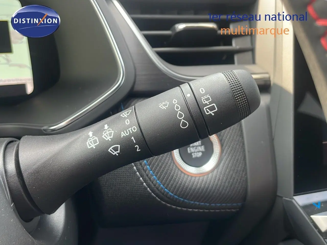 Gros plan sur la commande des essuie-glaces du Renault Captur E-Tech gris Cassiopée, avec bouton start/stop en arrière-plan.