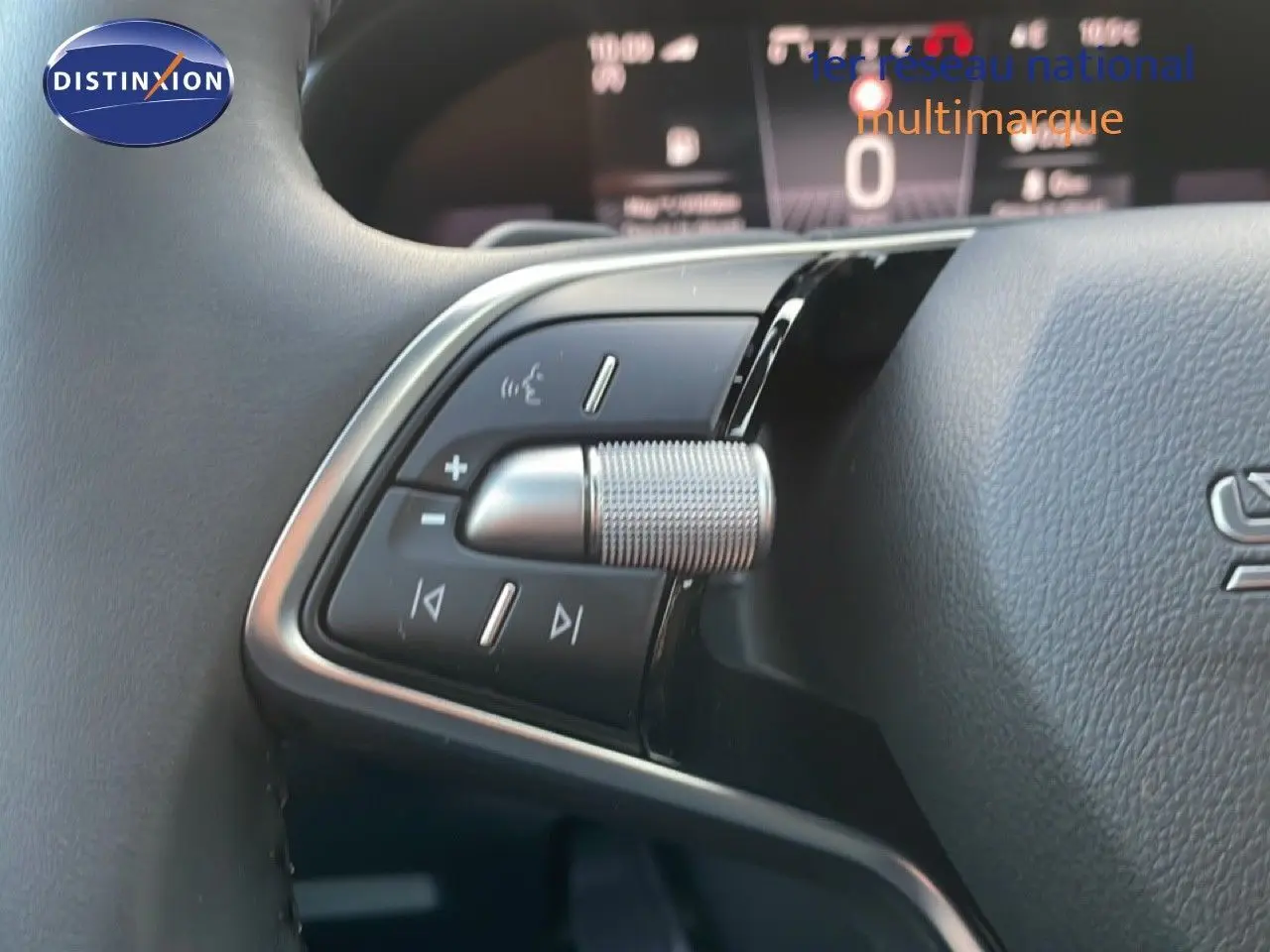 Gros plan sur les commandes multifonctions au volant d'un Skoda Kamiq gris argent, avec tableau de bord numérique en arrière-plan.