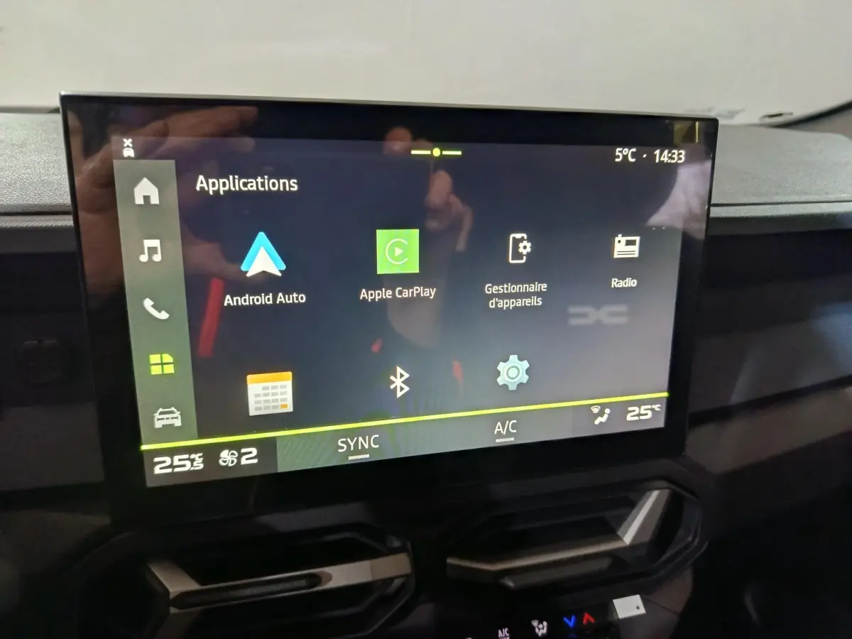 Écran tactile central affichant les applications Apple CarPlay et Android Auto dans l'habitacle du Dacia Bigster gris foncé.