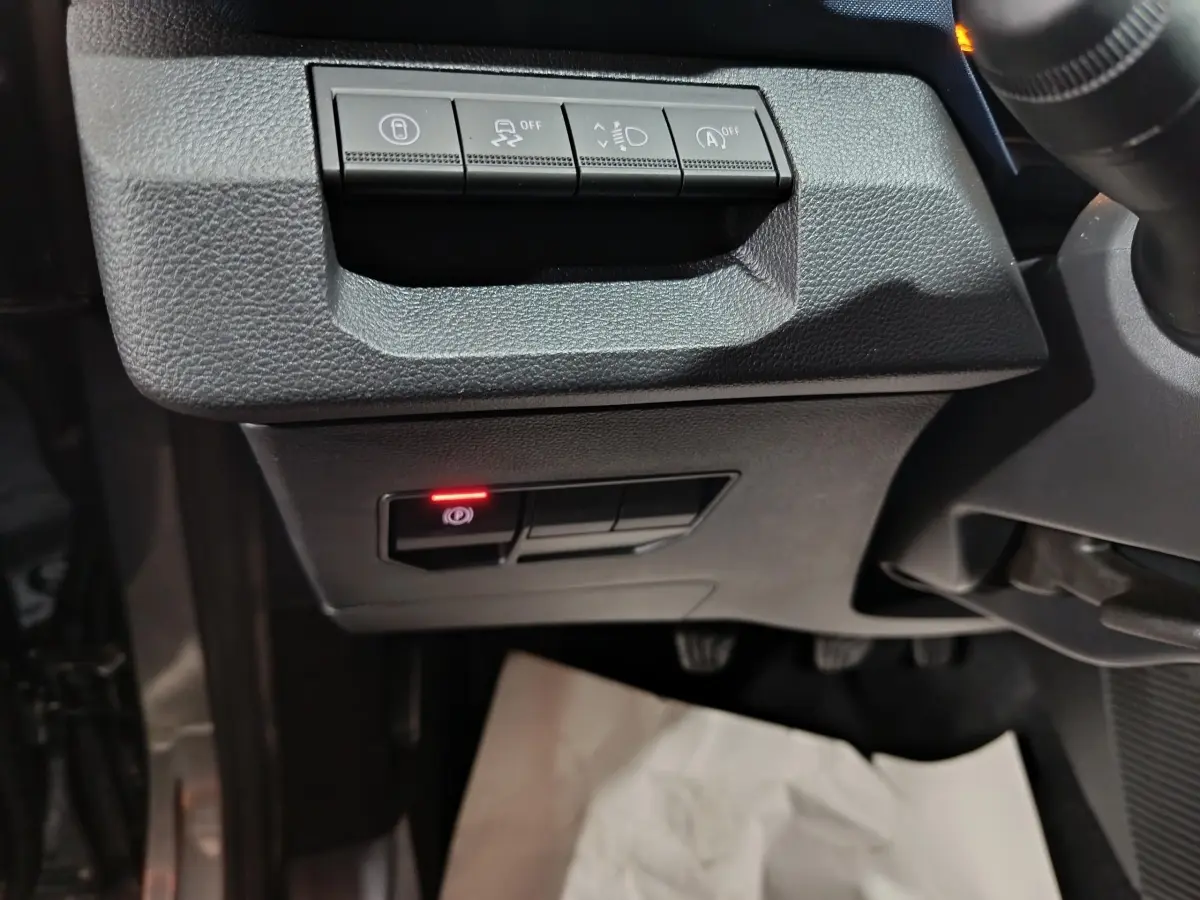 Détail intérieur côté gauche du tableau de bord gris foncé du Dacia Bigster 2025 avec commandes électroniques et frein à main activé.