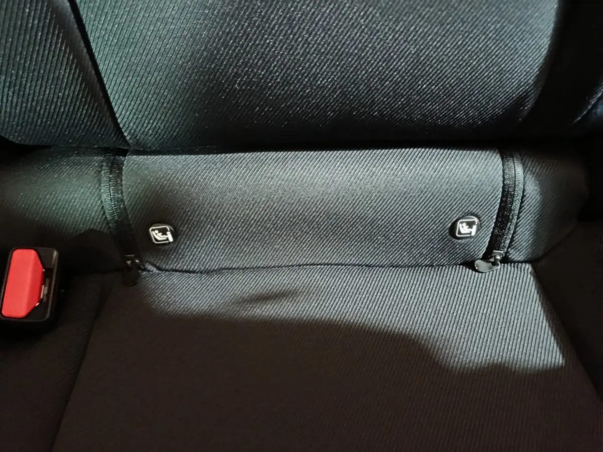 Gros plan sur la banquette arrière noire du Dacia Bigster avec attaches Isofix visibles et ceinture rouge partiellement montrée.