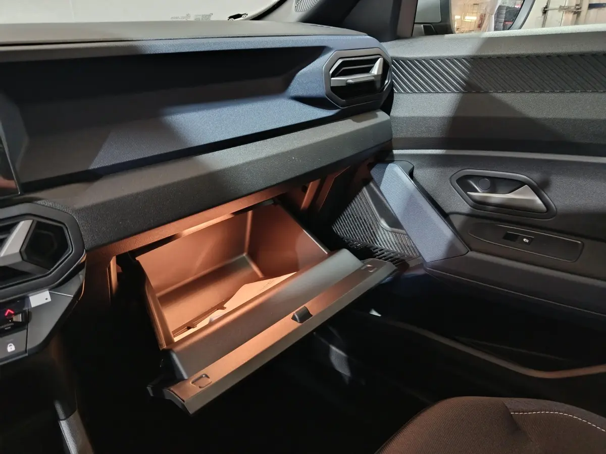Vue intérieure côté passager du tableau de bord gris foncé du Dacia Bigster 2025 avec boîte à gants ouverte.