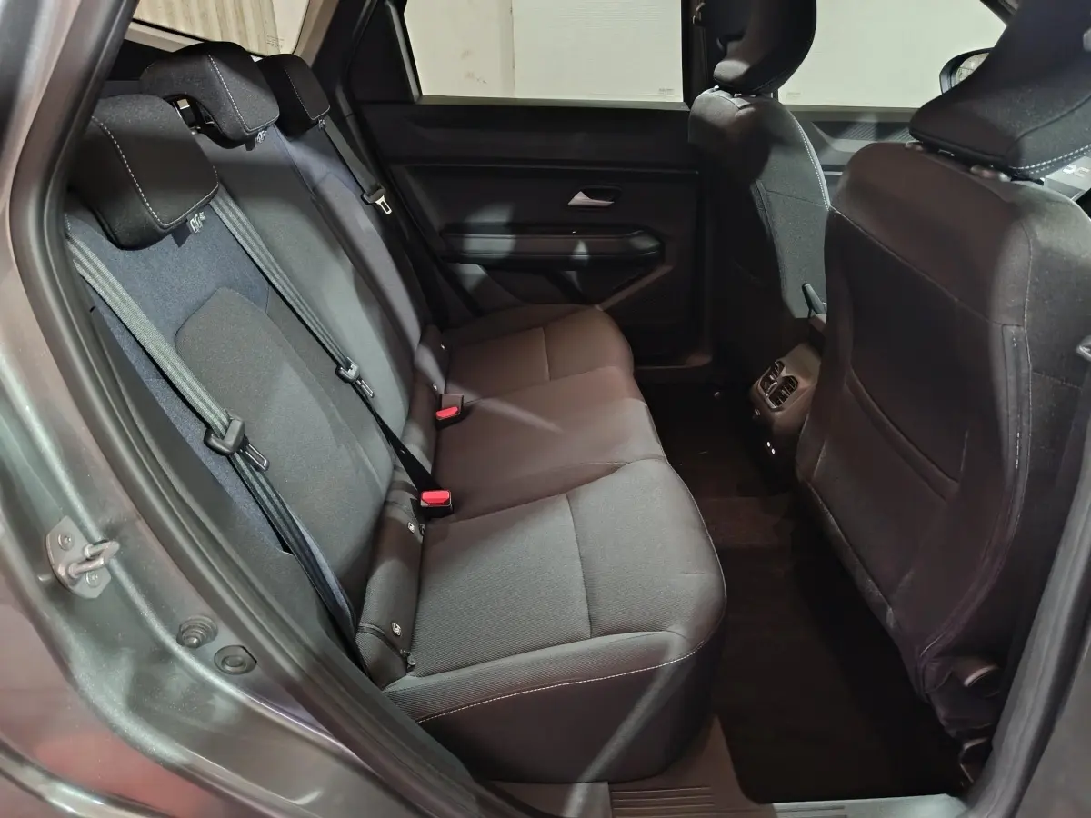 Vue intérieure arrière côté gauche du Dacia Bigster gris foncé, montrant la banquette trois places en tissu noir.