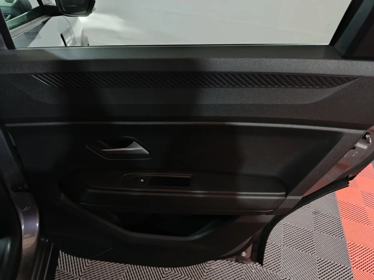 Vue intérieure du panneau de porte côté gauche gris foncé du Dacia Bigster 2025 avec poignée et commande de vitre électrique.