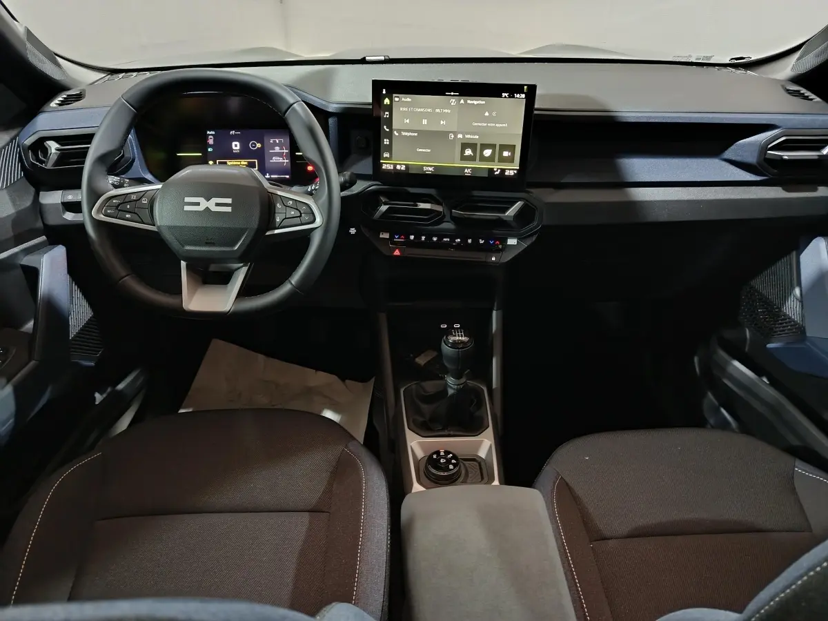 Vue intérieure avant du tableau de bord et volant du Dacia Bigster 2025 avec écran tactile et boîte manuelle.