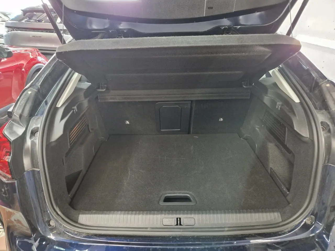 Coffre ouvert vu de l'arrière d'une Citroën C4 2024 bleu Eclipse avec toit noir Perla, intérieur noir.