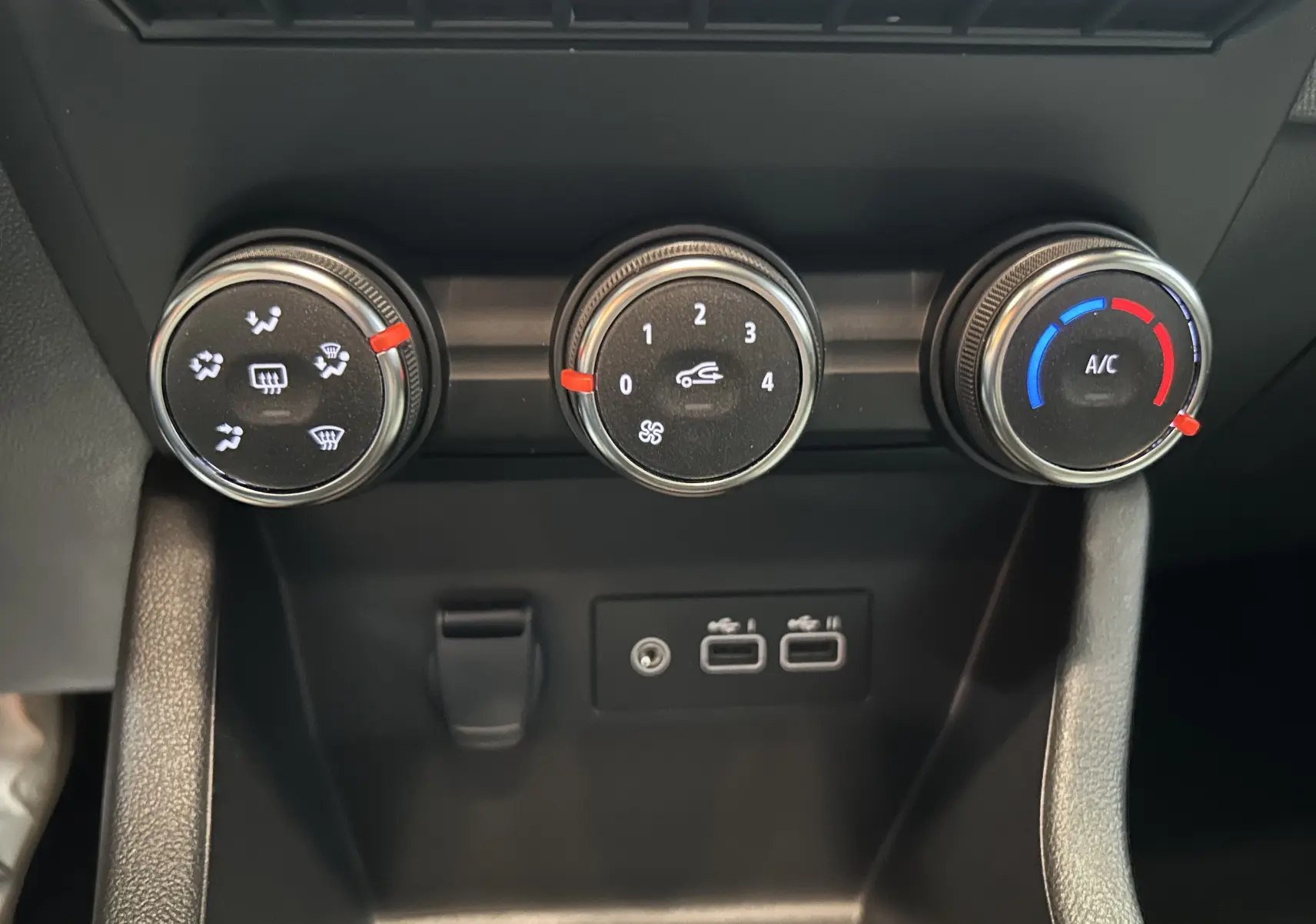 Vue rapprochée des commandes de climatisation et des ports USB sur la console centrale d’une Renault Clio V blanche.